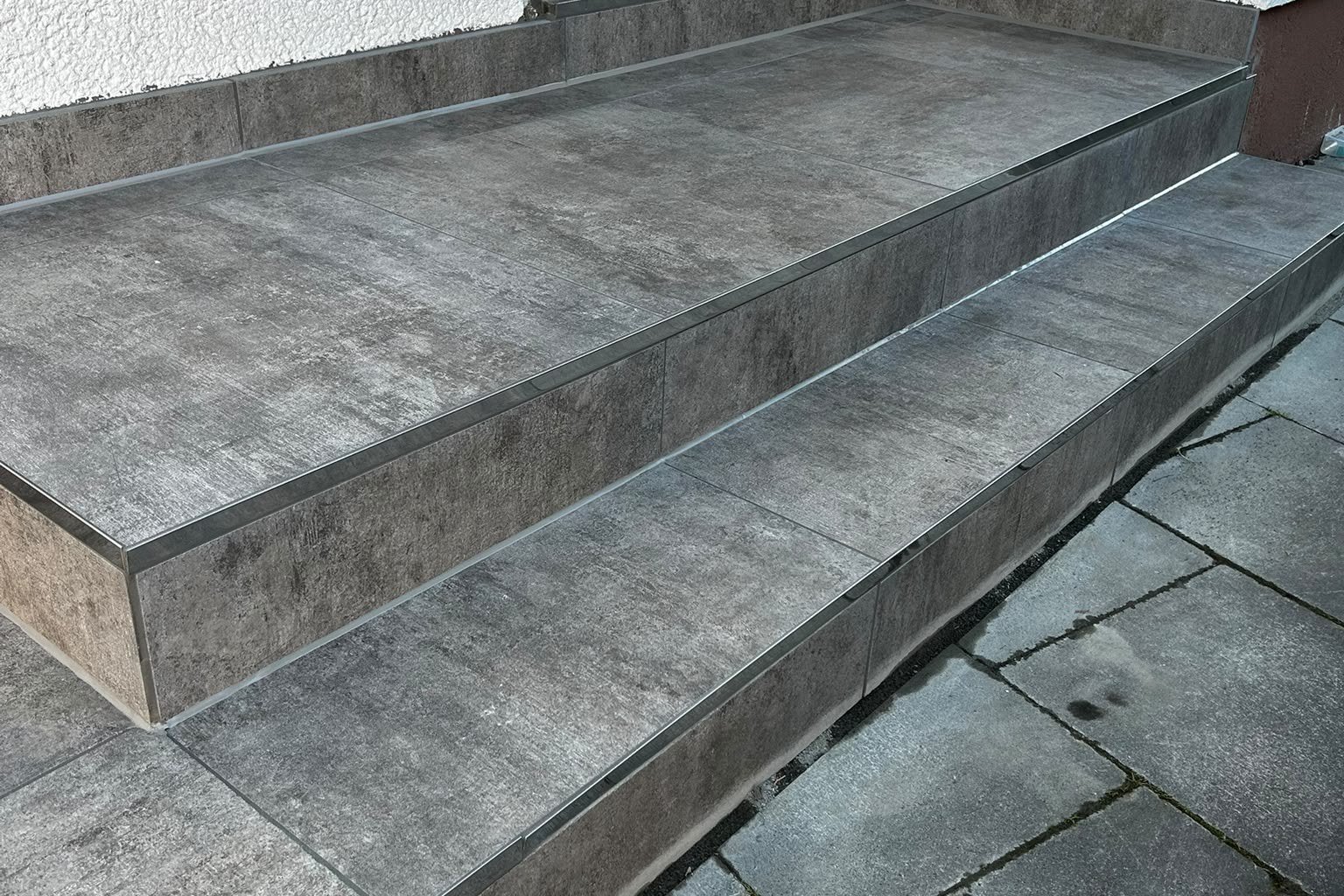 Hauseingang mit Stufen aus Feinsteinzeug in Betonoptik und Edelstahl-Kantenprofilen
