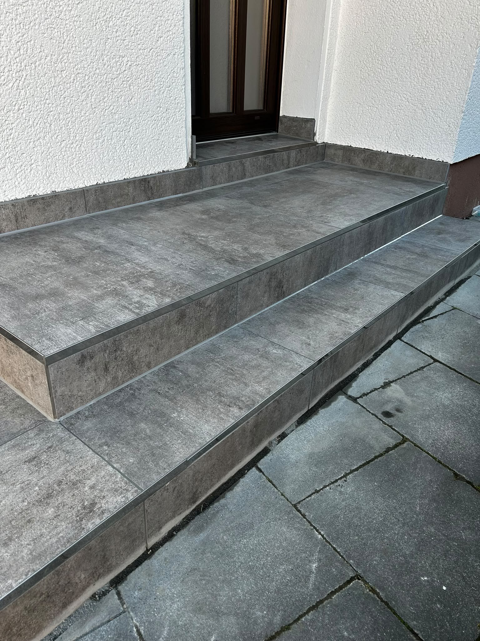 Hauseingang mit Stufen aus Feinsteinzeug in Betonoptik und Edelstahl-Kantenprofilen